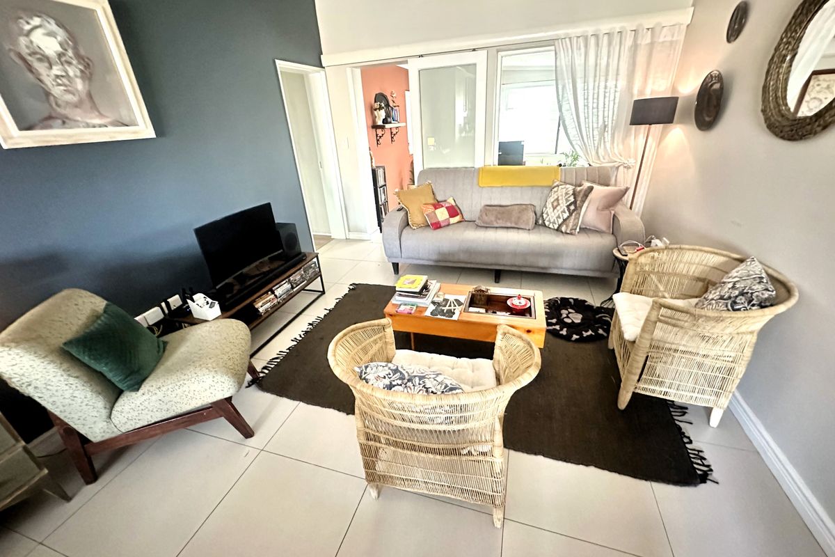 A comfortable living room featuring tiled flooring, a wall-mounted air conditioning unit, and sliding glass doors leading to an adjacent space.