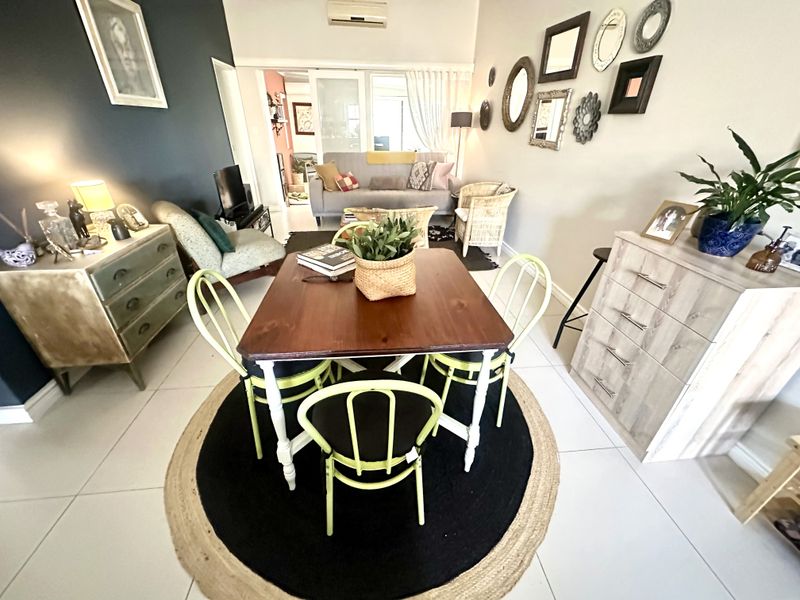 An open-plan living and dining area featuring tiled flooring, air conditioning, and sliding glass doors leading to an adjacent space.