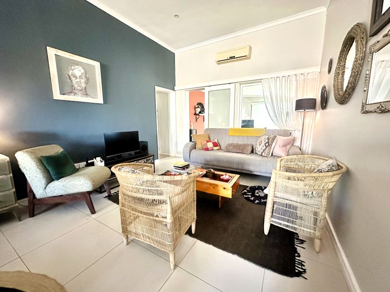A comfortable living room featuring tiled flooring, a split-system air conditioner, and sliding glass doors that provide natural light and access to the outdoors.