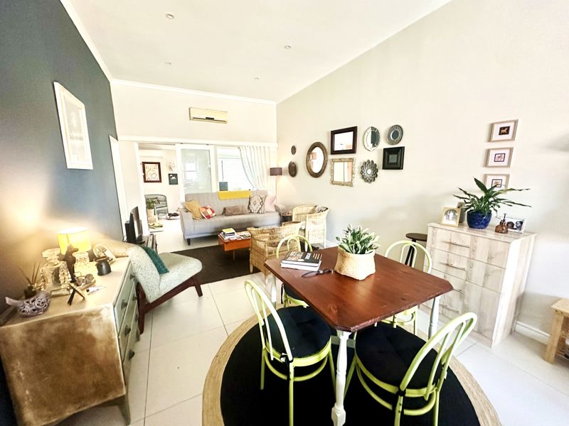 An open-plan living and dining area featuring tiled flooring, recessed lighting, and a split-system air conditioner, with direct access to an adjoining space.