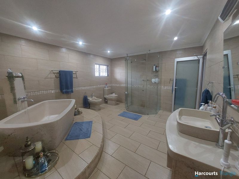 Spacious modern bathroom featuring a raised platform with a freestanding bathtub, glass-enclosed shower, bidet, toilet, and a contemporary vessel sink vanity.