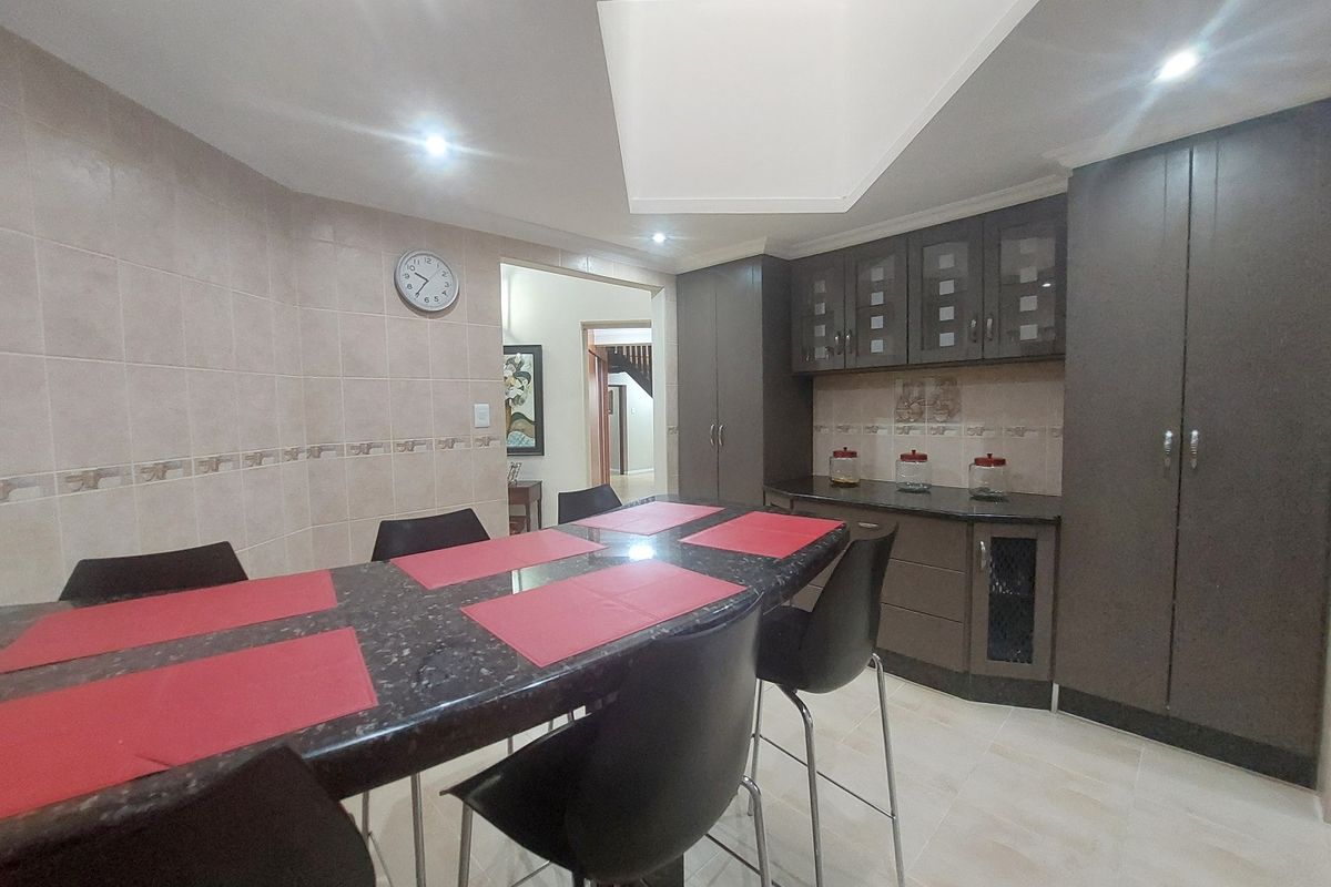 A functional kitchen area featuring dark built-in cabinetry, granite countertops, a tiled backsplash, and a skylight providing natural illumination.
