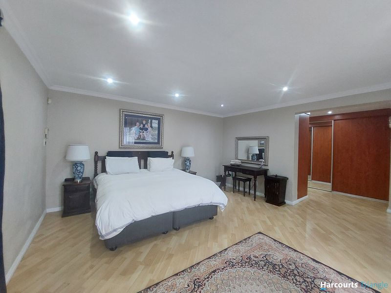 Spacious bedroom featuring light wood herringbone flooring, recessed downlighting, and integrated built-in cupboards with sliding doors.