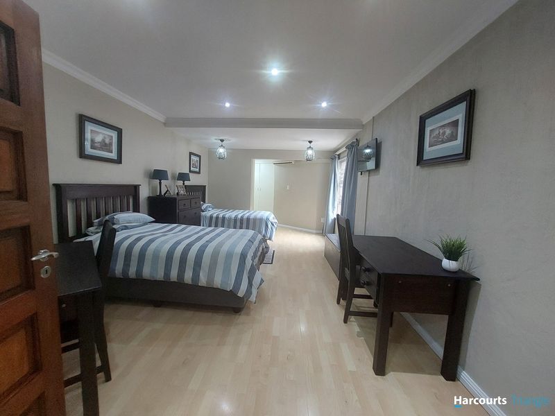 Spacious bedroom featuring light laminate flooring, recessed downlighting, and built-in storage, offering a comfortable and well-maintained living space.