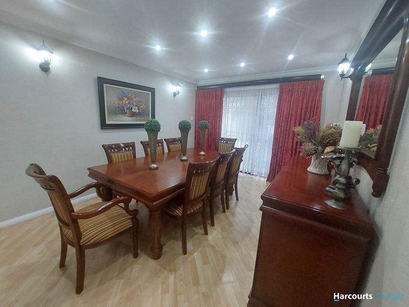 A formal dining room featuring laminate flooring, recessed downlighting, wall sconces, and a sliding glass door providing access to the exterior.