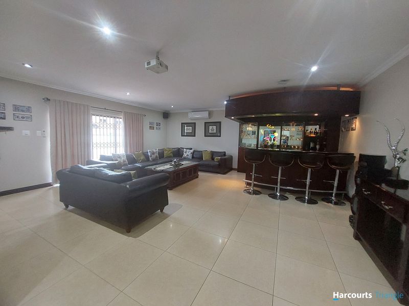 Spacious entertainment area featuring a built-in bar, tiled flooring, recessed lighting, and integrated air conditioning, ideal for hosting and relaxation.