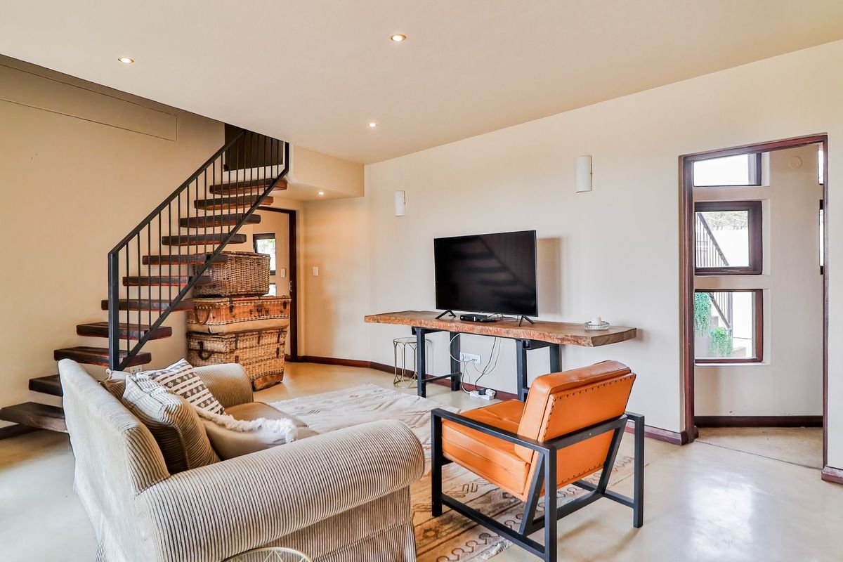 Spacious living room featuring a modern metal staircase, recessed lighting, and polished concrete flooring, creating a warm and inviting atmosphere.