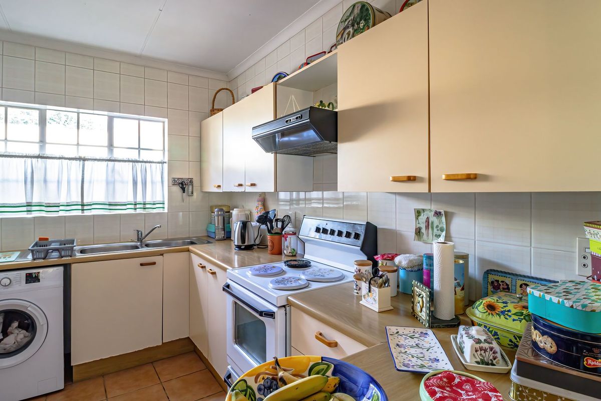 Functional kitchen featuring tiled splashbacks, laminate countertops, built-in cabinetry, and a dedicated space for laundry appliances.