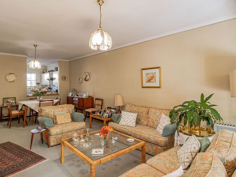 Spacious open-plan living and dining area featuring neutral walls, classic pendant lighting, and a seamless flow into the adjacent kitchen space.
