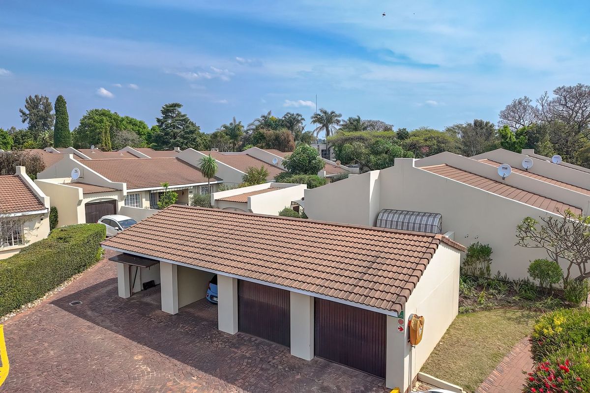 Aerial view of a retirement village complex featuring multiple residential units with tiled roofs, paved driveways, and integrated garage and carport facilities.
