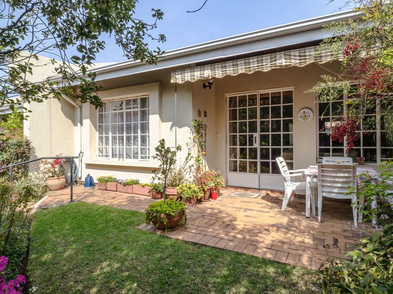 A well-maintained rear patio area featuring brick paving, a retractable awning, and direct access to the home through classic french doors.