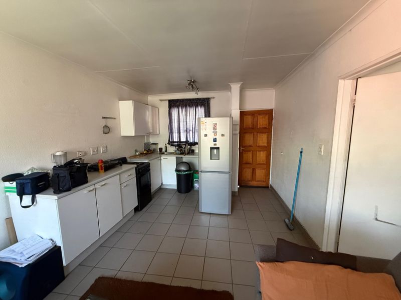 A functional kitchen area featuring tiled flooring, built-in cabinetry, and a freestanding stove, offering a practical layout for daily meal preparation.