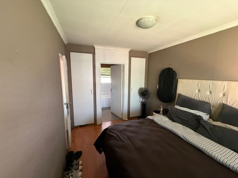 A bedroom featuring built-in cupboards, laminate flooring, and direct access to an en-suite bathroom.