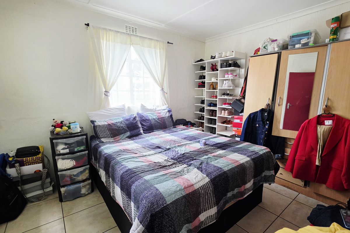 A functional bedroom featuring tiled flooring, a built-in wardrobe, and a dedicated shelving unit for storage.