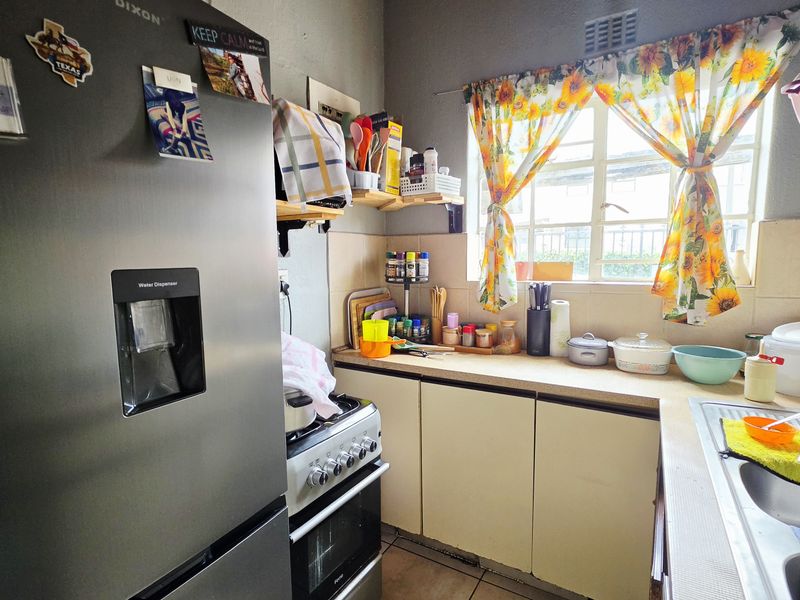 A compact kitchen featuring built-in cabinetry, a stainless steel sink, and a freestanding stove, offering a functional layout with potential for modernization.
