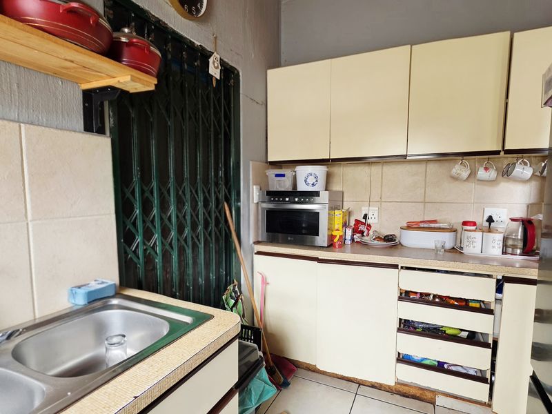 Compact kitchen featuring laminate countertops, tiled backsplash, and built-in cabinetry, requiring cosmetic updates to improve functionality and aesthetic appeal.