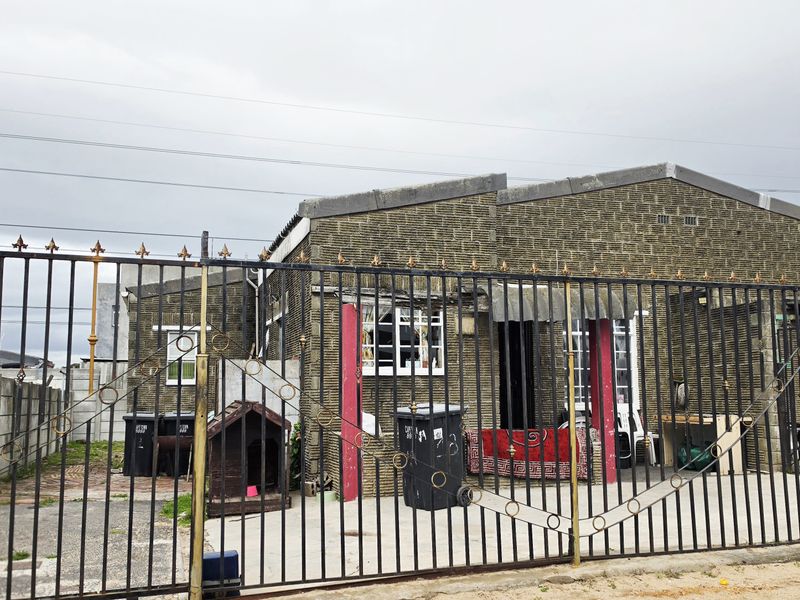 Front elevation of a townhouse featuring a concrete block facade, secured by a full-height wrought iron gate and perimeter boundary wall.