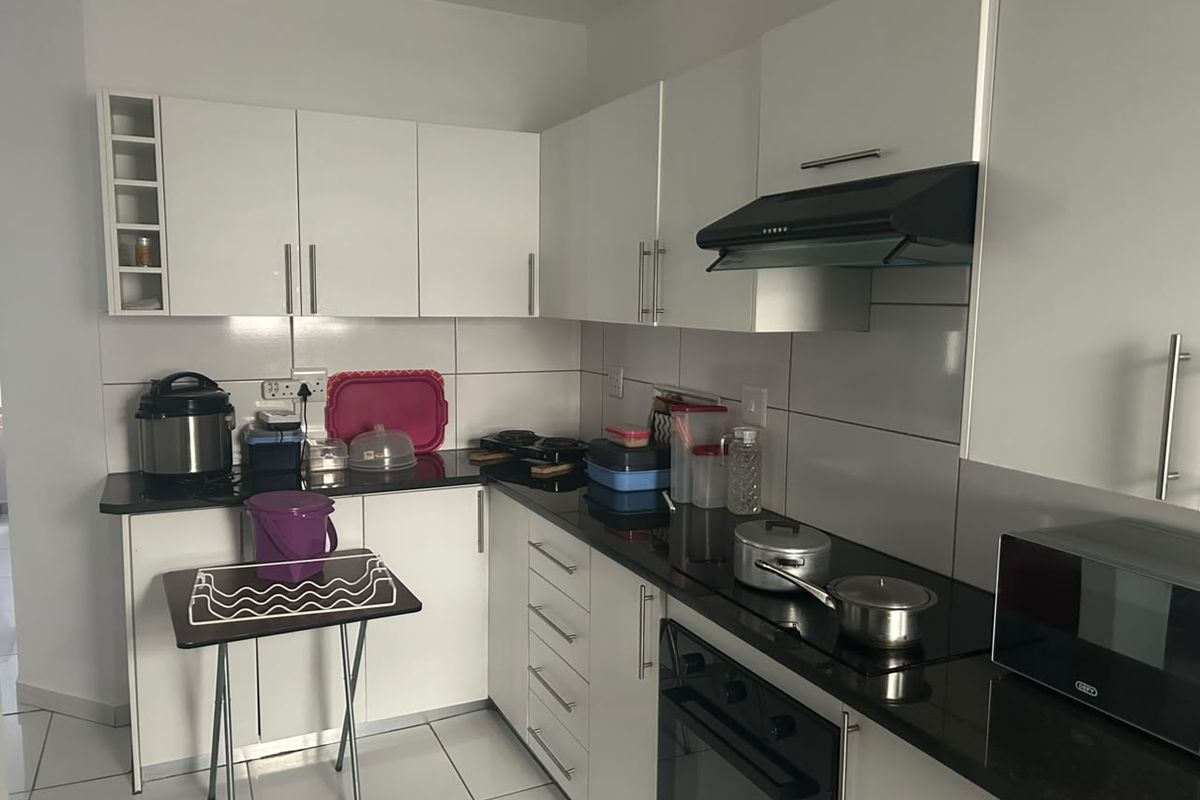 A functional kitchen featuring white cabinetry, black granite countertops, a built-in oven, electric hob, and a modern extractor fan with tiled finishes.
