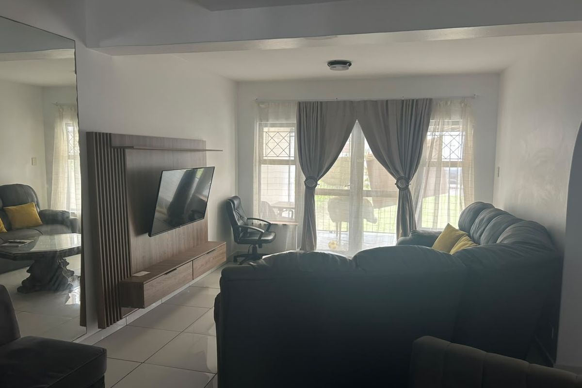 A living room featuring tiled flooring, a built-in media unit, and a sliding glass door providing access to the exterior.