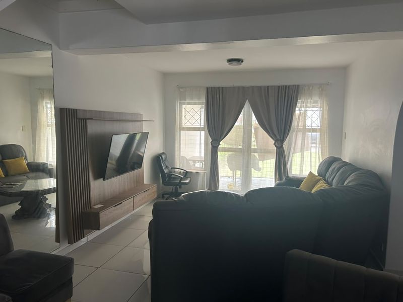A living room featuring tiled flooring, a built-in media unit, and a sliding glass door providing access to the exterior.