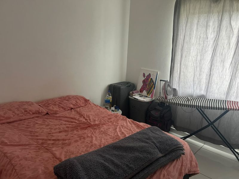 A standard bedroom featuring tiled flooring and a window with curtain treatments, providing a functional space for rest.