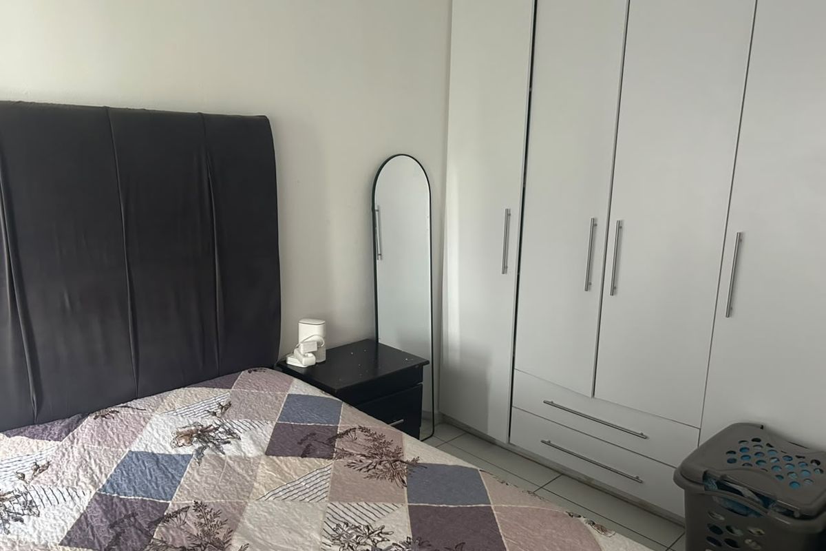 A bedroom featuring a white built-in wardrobe with modern handles, providing ample storage space.
