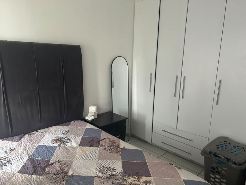 A bedroom featuring a white built-in wardrobe with modern handles, providing ample storage space.