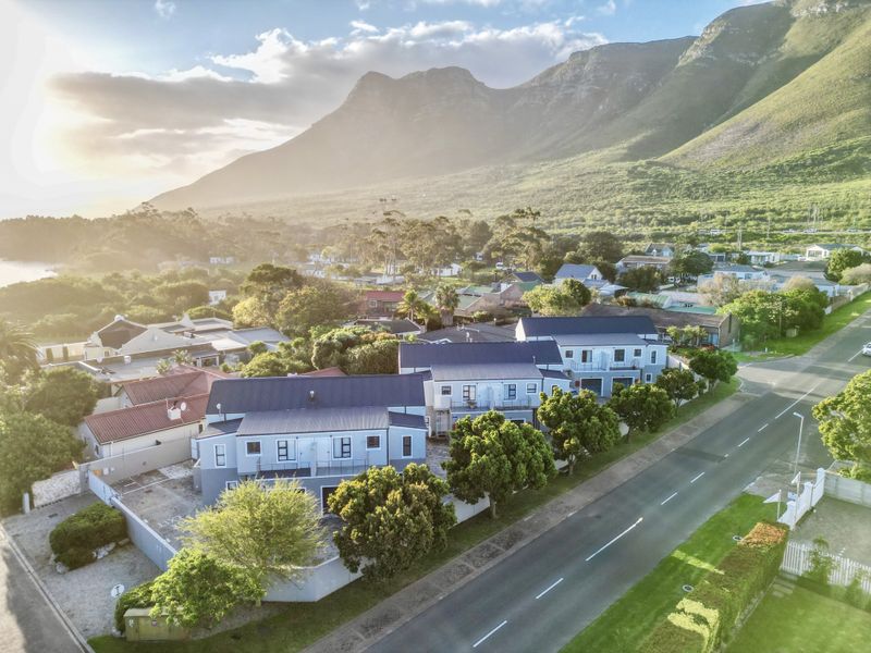 Aerial view of a townhouse complex featuring metal roofing, paved driveways, and balconies, set against a scenic mountain backdrop.