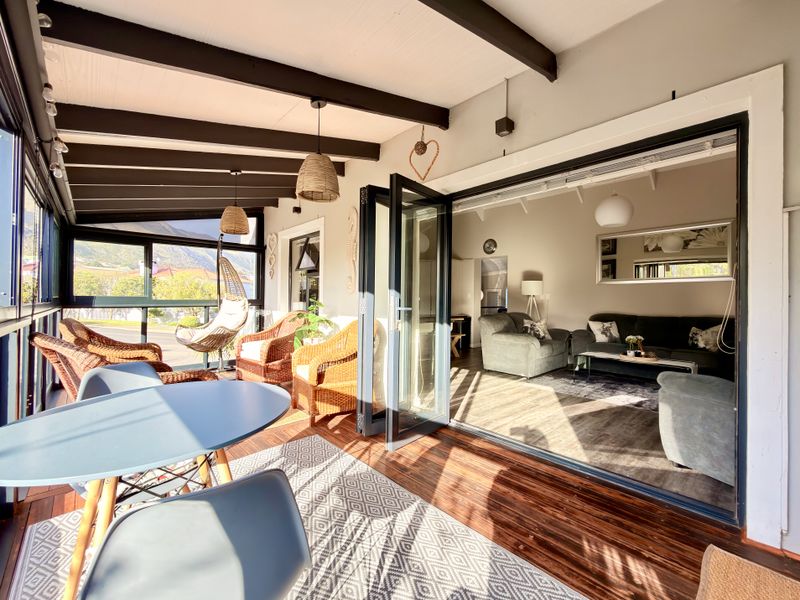 A bright, covered patio featuring timber decking and exposed beams, seamlessly connected to the living area through large bi-fold doors.