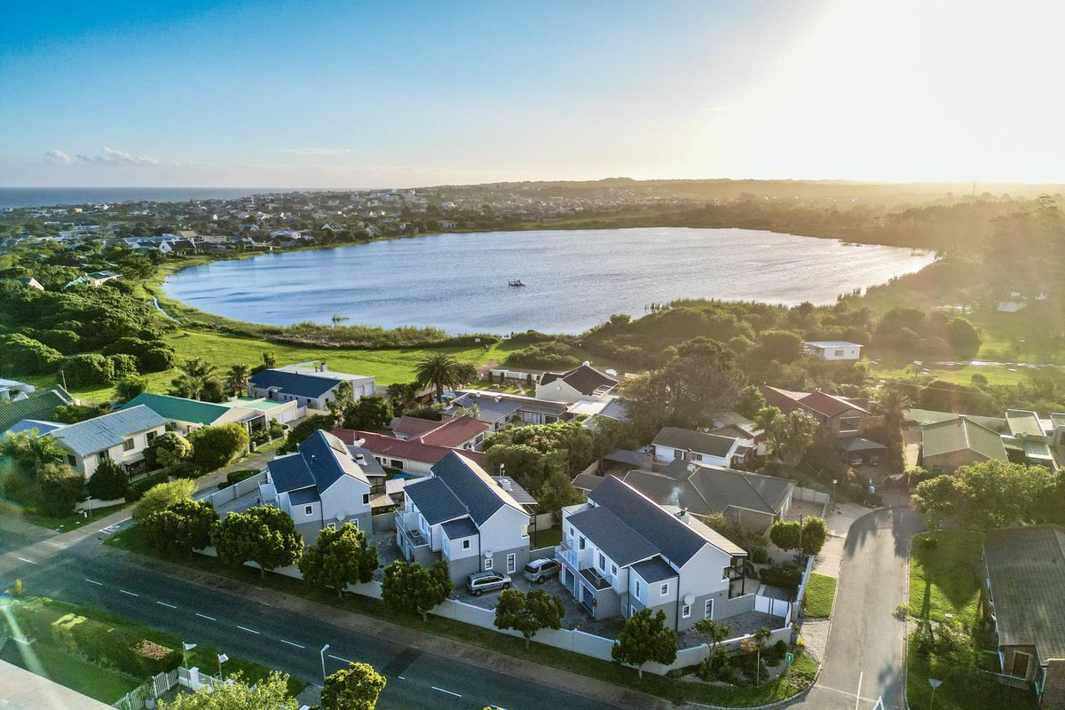 An aerial view of a residential townhouse complex situated near a scenic lake, showcasing the surrounding neighborhood and landscape.