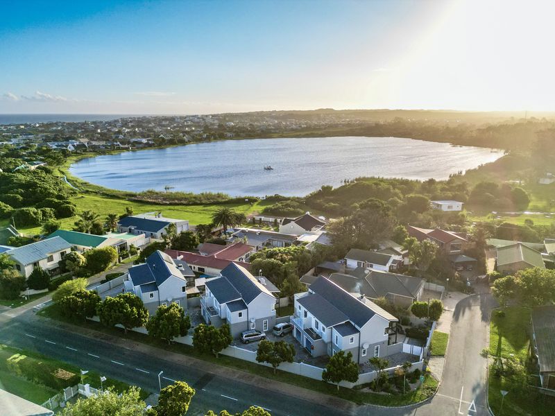 An aerial view of a residential townhouse complex situated near a scenic lake, showcasing the surrounding neighborhood and landscape.