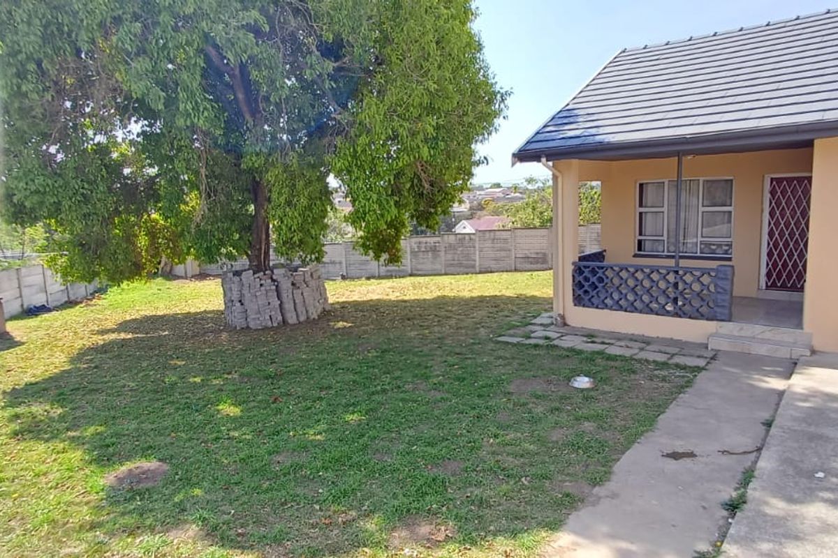 Rear garden area featuring a covered patio, brick braai, and perimeter precast walling with established trees.