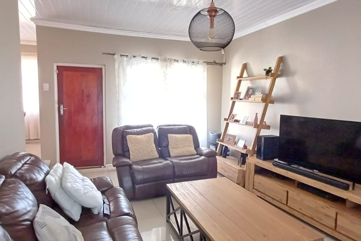 A comfortable living room featuring tiled flooring and a classic tongue and groove ceiling, providing a functional and inviting space.