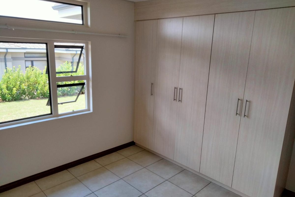 A bright, empty bedroom featuring neutral tiled flooring and extensive built-in cupboards, offering a clean and versatile space.