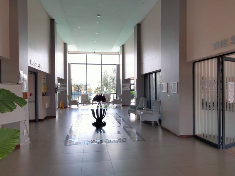 Spacious retirement village clubhouse reception area featuring high ceilings, large windows for natural light, and elegant tiled flooring with a central decorative inlay.