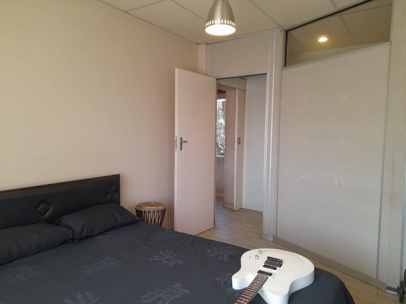 A bedroom featuring a drop ceiling, partition walling, and an internal door leading to an adjacent space.