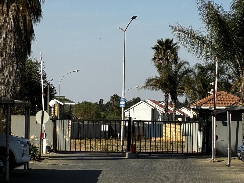 A view of the secure entrance gate and paved driveway leading into the apartment complex.