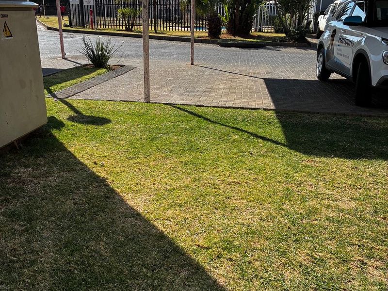 Exterior view of the property featuring a paved driveway, a covered carport structure, and a maintained lawn area.