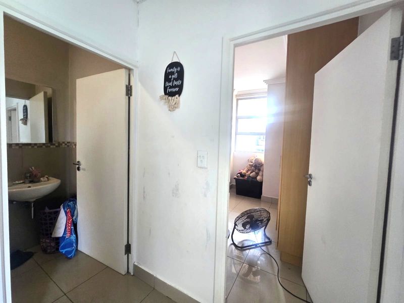 A functional hallway connecting a bathroom and bedroom, featuring tiled flooring and built-in storage, requiring minor cosmetic updates to wall finishes.