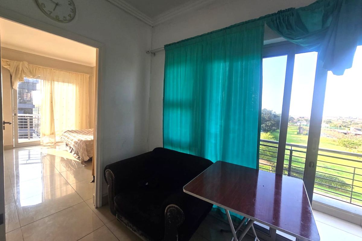 Living area featuring tiled flooring and a sliding glass door providing access to a balcony with outdoor views.
