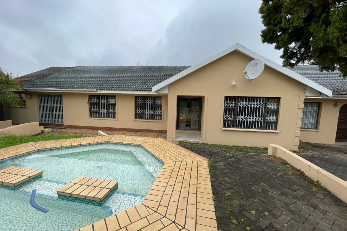 Rear exterior view featuring a swimming pool with tiled surround, paved patio area, and security gates on windows.