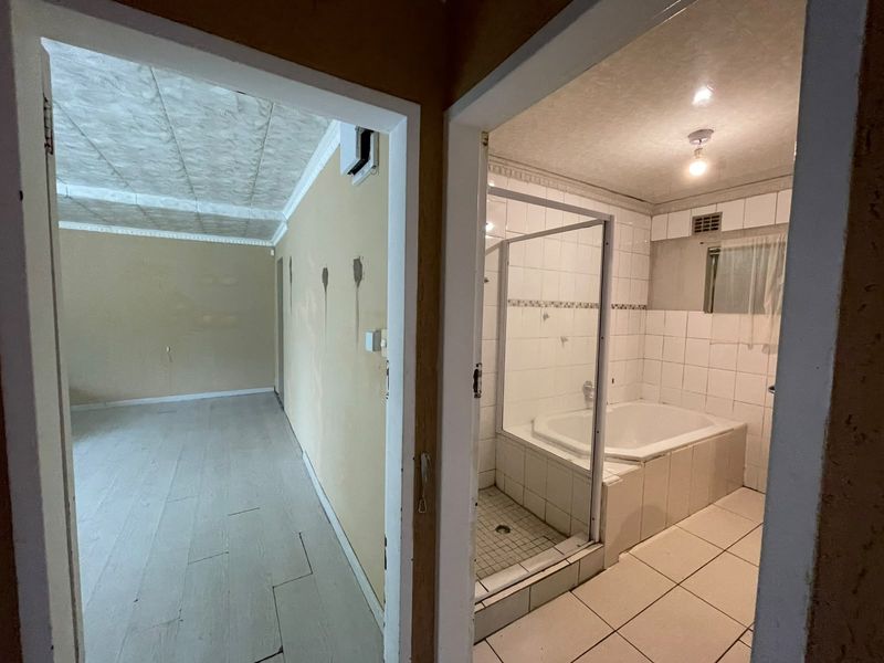 A dated bathroom featuring a built-in bathtub and separate shower enclosure, requiring cosmetic updates to modernize the space.