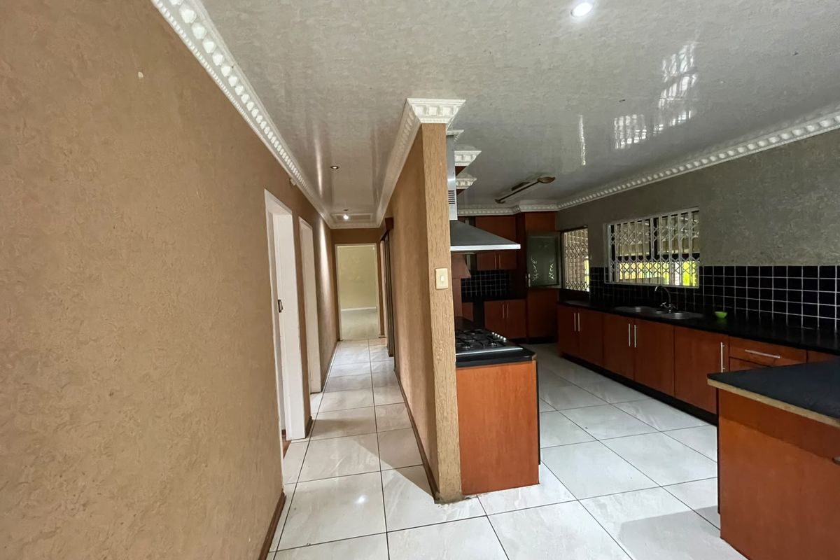 Spacious kitchen featuring built-in wooden cabinetry, gas hob, extractor fan, and tiled flooring, offering a functional layout with ample storage space.