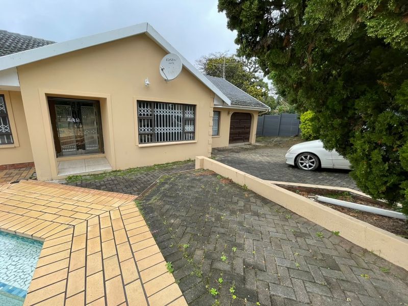 Rear exterior view of the house featuring a swimming pool, paved driveway, and secure access points with security gates.