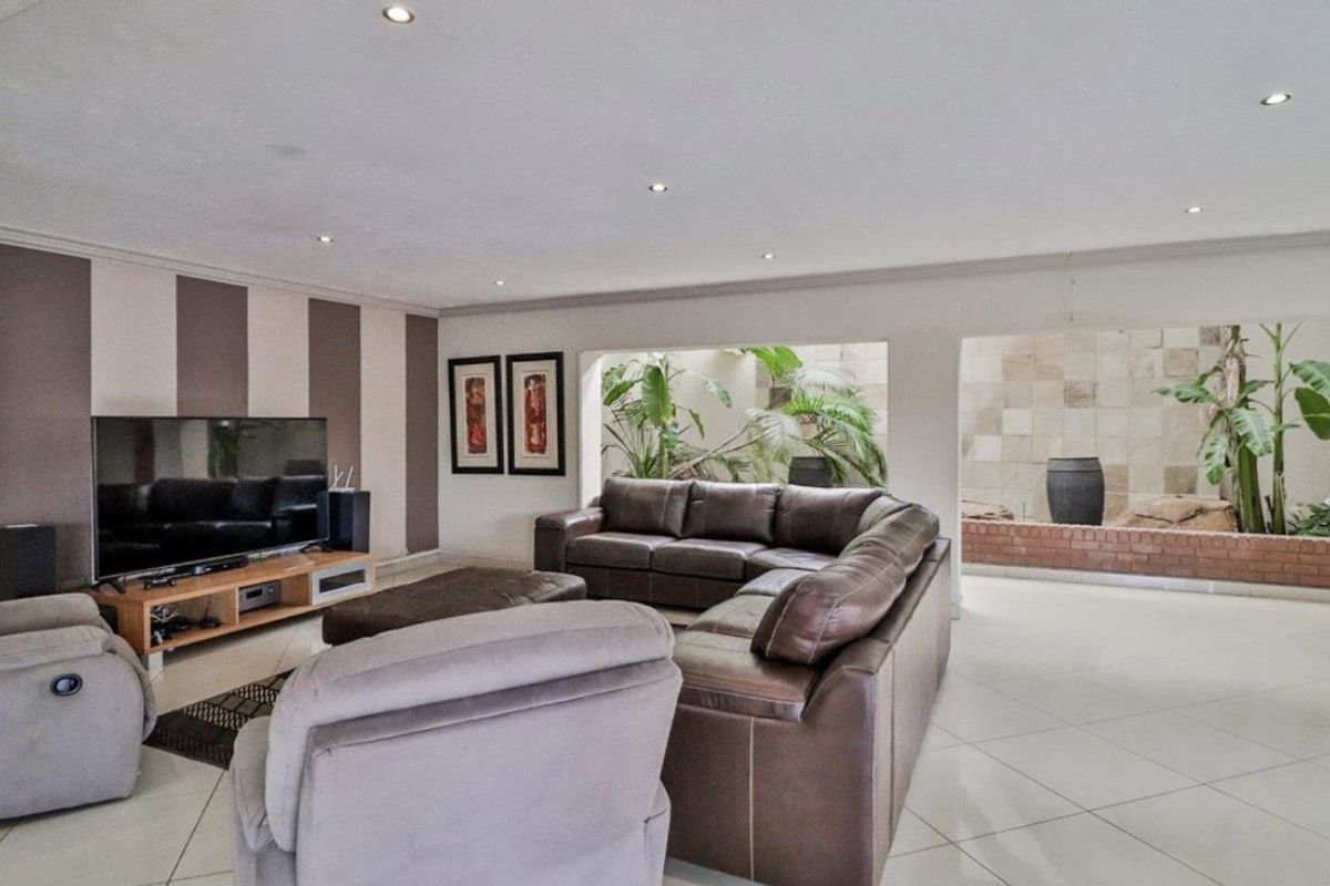 Spacious living room featuring tiled flooring, recessed downlights, and a unique internal courtyard view, providing a bright and open atmosphere.