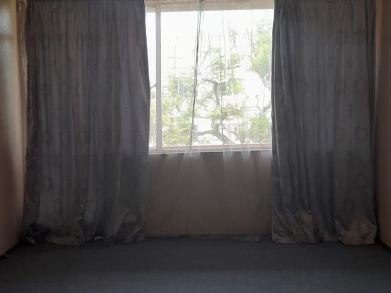 An empty bedroom featuring a crystal chandelier and carpeted flooring, offering a blank canvas for potential renovation and interior design updates.
