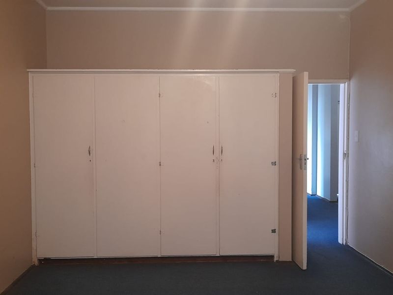A vacant bedroom featuring built-in cupboards and carpeted flooring, offering a blank canvas for potential updates and interior design improvements.