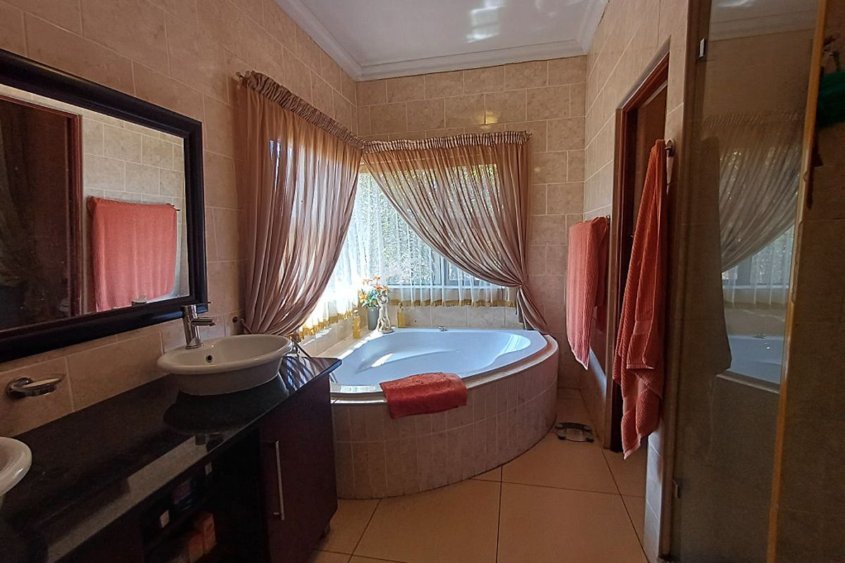 A functional bathroom featuring a corner bathtub, vessel sink with vanity cabinet, and tiled finishes throughout.
