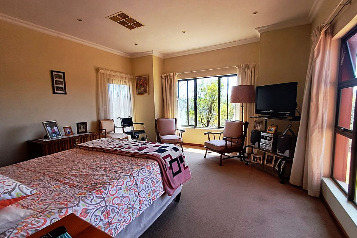 Spacious bedroom featuring neutral walls, carpeted flooring, and large windows providing natural light and garden views.