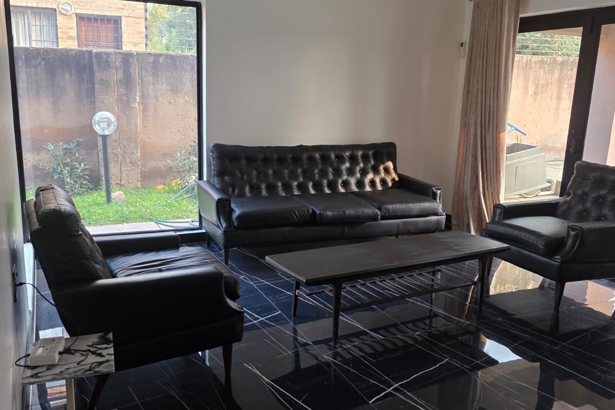 Modern living room featuring high-gloss black marble-look floor tiles, recessed lighting, a wall-mounted air conditioning unit, and large windows providing natural light.